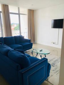 uma sala de estar com um sofá azul e uma mesa de vidro em Uptown Accommodations em Windhoek