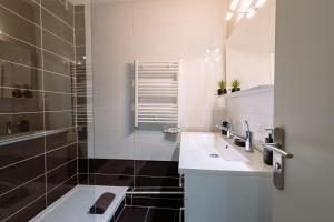 La salle de bains blanche est pourvue d'un lavabo et d'une douche. dans l'établissement L'Évêché - Grand T3 en hyper-centre, à Castres