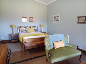 un dormitorio con una cama y una silla en Drakensberg Mountain Retreat, en Bergville