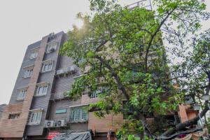 un edificio alto con un árbol delante de él en Super OYO Krishna Guest House en Calcuta