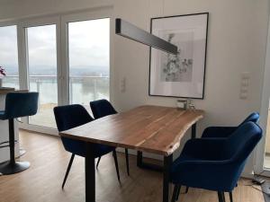 een eetkamer met een houten tafel en blauwe stoelen bij Moselblick Penthouse mit Terrasse in Koblenz