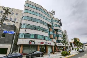 東海的住宿－Hotel Yeogiuhtte Donghae Mukho，一座高大的建筑,前面有汽车停放