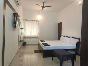 um quarto com uma cama e uma ventoinha de tecto em ARIVU LODGE AC em Coimbatore