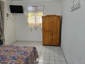 a bedroom with a bed and a wooden cabinet at Au Paradis Créole in Dubédou