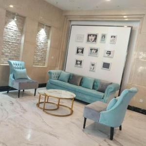 ein Wohnzimmer mit einem blauen Sofa und 2 Stühlen in der Unterkunft Xana Hotelle Yining Airport Road Jinwuyuan in Kipekyüzi