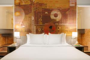 1 dormitorio con 1 cama blanca grande y un mural en Crown Hotel Eindhoven Centre en Eindhoven