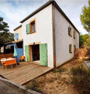 ein Haus mit einer Holzterrasse davor in der Unterkunft Maison calme + piscine + pinède + parking in Castries