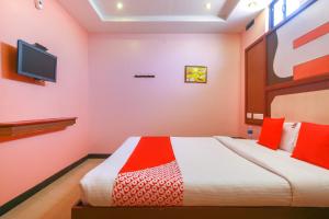 a bedroom with a bed and a tv on the wall at OYO Gnana S.R.M Residency in Pondicherry