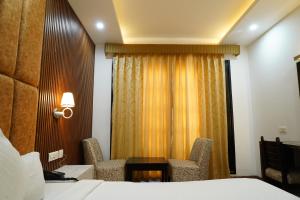 une chambre d'hôtel avec un lit, une table et des chaises dans l'établissement Hotel Raunak, à Pinjaur