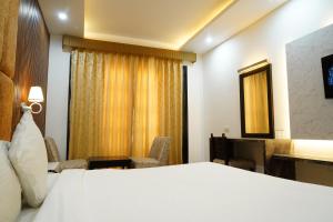 Cette chambre comprend un lit blanc et un bureau. dans l'établissement Hotel Raunak, à Pinjaur