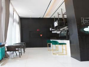 un restaurant avec des murs noirs et des chaises et des tables vertes dans l'établissement Xana Hotelle Nanchang Xinhongcheng Grand Market Metro Station, à Taohua