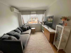 a living room with a couch and a large window at Sydney city meets village living in Sydney