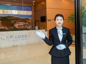a woman in a suit standing in front of a sign at Chonpines Hotel Jining Quanmin Fitness Plaza in Jining