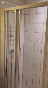 a shower in a bathroom with white tiles at Solace Apartment, Oslo Downtown in Oslo