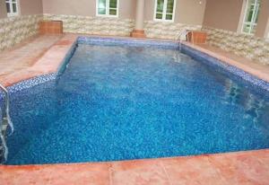 a large swimming pool with blue water at Ayoluyem Aparthotel and Suites in Ogbodo