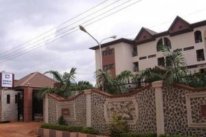 a building with a fence in front of a house at Roban Hotels Ltd in Enugu