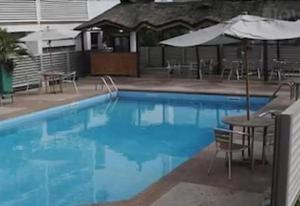 una gran piscina azul con mesas y sombrillas en Top Rate Hotel en Owerri