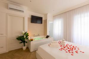 a white bedroom with a tub and a bed with red petals at FARNESINA SUITE in Rome