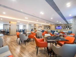 a restaurant with orange chairs and tables in a room at City Comfort Inn Wuhan Tianhe Airport Outlets in Huanghualao