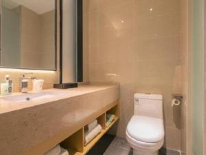 a bathroom with a toilet and a sink and a mirror at City Comfort Inn Wuhan Tianhe Airport Outlets in Huanghualao