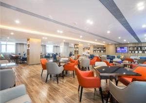 restauracja z pomarańczowymi krzesłami i stołami w pokoju w obiekcie Echarm Hotel Wuhan Tianhe Airport Outlets w mieście Huanghualao