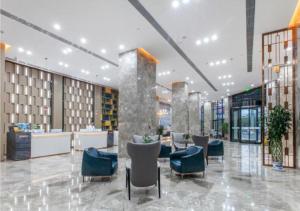 a lobby with chairs and tables in a building at Echarm Hotel Wuhan Tianhe Airport Outlets in Huanghualao