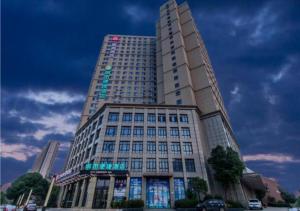 un edificio alto con un cartel en la parte delantera en Echarm Hotel Wuhan Tianhe Airport Outlets en Huanghualao