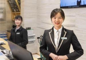 a woman in a suit standing in front of a laptop at City Comfort Inn Chengdu Dongjiao Memory in Chengdu