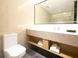 uma casa de banho com um lavatório, um WC e um espelho. em City Comfort Inn Haikou Xiuying District Wanda Plaza em Pin-lien