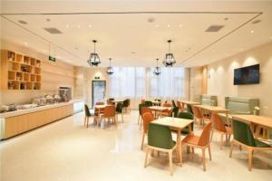 昆明市にあるCity Comfort Inn Kunming Xinluojiu Bay Guangju Roadのテーブルと椅子のあるレストラン、カフェテリア