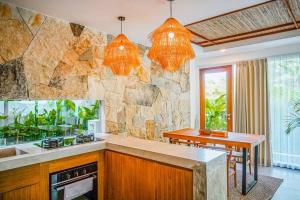 une cuisine avec un comptoir et un mur en pierre dans l'établissement Serene 2BR Villa with Lush View 5 mins to Beach, à Tanah Lot