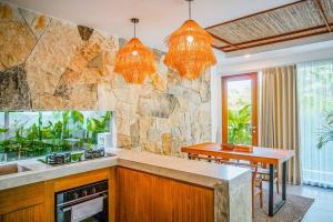 una cucina con bancone e parete in pietra di Serene 2BR Villa with Lush View 5 mins to Beach a Tanah Lot