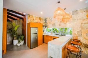 una cucina con frigorifero e bancone con sgabelli di Serene 2BR Villa with Lush View 5 mins to Beach a Tanah Lot Altre 4 foto
