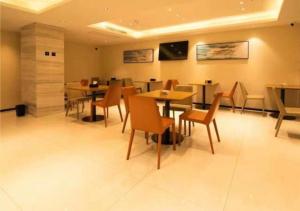 comedor con mesas y sillas de madera en City Comfort Inn Changsha Outlets Datuo Metro Station en Muyun