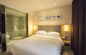 a bedroom with a white bed and a bathroom at City Comfort Inn Changsha High Speed Railway Station in Yangtianhu