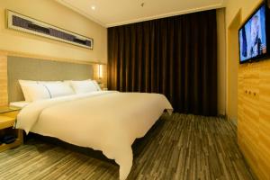 a bedroom with a large white bed and a television at City Comfort Inn Changsha High Speed Railway Station in Yangtianhu
