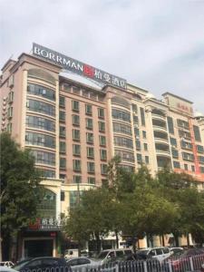 a hotel building with cars parked in front of it at Borrman Hotel Maoming 7th Youcheng Road Municipal Government in Maoming