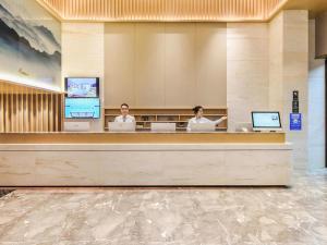 two people sitting at a counter in a hotel lobby at City Comfort Inn Guiyang Airport Future Ark in Guiyang
