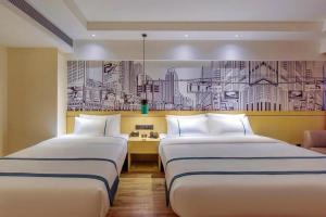 duas camas num quarto de hotel com um desenho na parede em City Comfort Inn Guiyang Airport Future Ark em Guiyang