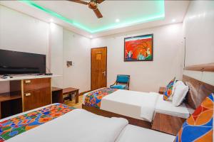 a hotel room with two beds and a flat screen tv at FabHotel Prime Stay inn I in Varanasi