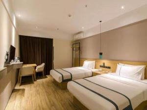 ein Hotelzimmer mit 2 Betten und einem Schreibtisch in der Unterkunft City Comfort Inn Xiaogan Hubei Engineering College in Xiaogan