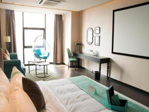 南昌市にあるXana Hotelle Nanchang Gaoxin Avenue Juren Internationalのベッド、テーブル、デスクが備わる客室です。