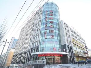 ein großes Gebäude mit Glasfenstern in einer Stadt in der Unterkunft Pai Hotel Ordos Dongsheng District Yingbin Road 