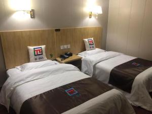 una habitación con 3 camas en una habitación de hotel en Pai Hotel Ordos Dongsheng District Yingbin Road 
