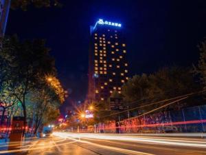 wysoki budynek z oświetleniem w nocy w obiekcie Magnotel Hotel Guangyuan Nanhe Bus Station Beijing Road w Guangyuan