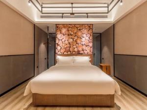 a bed in a room with a wall of logs at ZMAX Hotel Yan'an Baimi Avenue Baotashan in Qiao'ergou