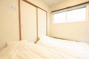 sypialnia z białym łóżkiem i oknem w obiekcie 函館ベイハウス-函館ベイエリアの観光に便利な 貸切住宅 w mieście Hakodate