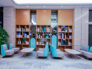 a library with blue chairs and tables and bookshelves at Xana Lite Huizhou Railway Station in Ruhu