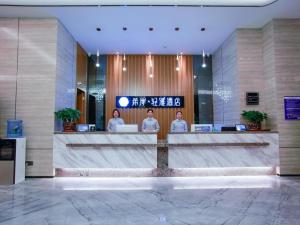 a lobby with three people standing at a desk at Xana Lite Huizhou Railway Station in Ruhu