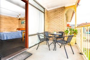 a patio with chairs and a table on a balcony at Town Centre Motor Inn in Merimbula